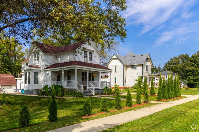 Sunlight peeks through the foliage of mature, leafy trees that shade green lawns in Sharon’s central village