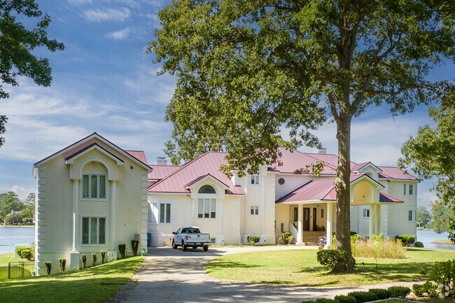 A large brick estate home in Linkhorn Park sits on a wooded lot near Little Neck Creek.