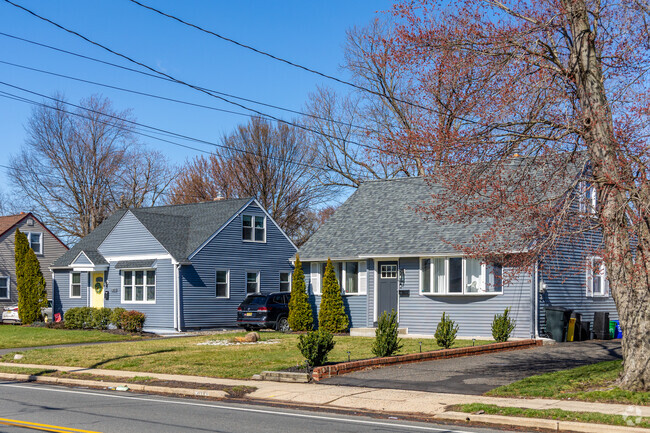 A pair of blue rambler style homes with well kept landscaping.