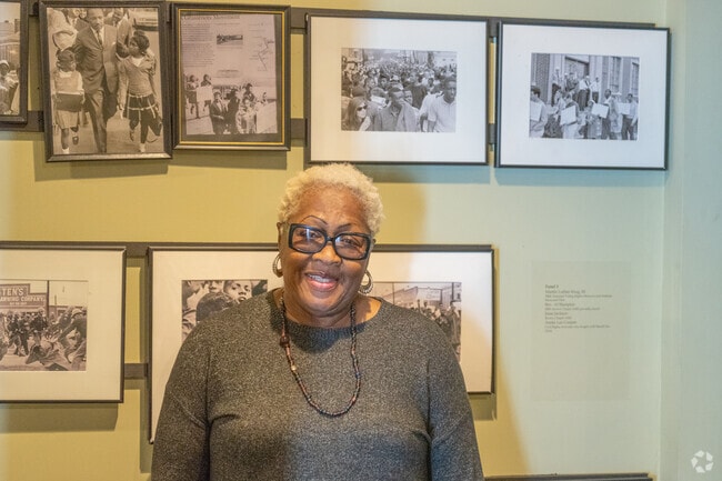 As she stands before her photograph captured during the historic march across the Edmund Pettus Bridge, this courageous foot soldier shares her powerful story at the Voting Rights Museum in Selma, embodying the spirit of resilience and the fight for justice.