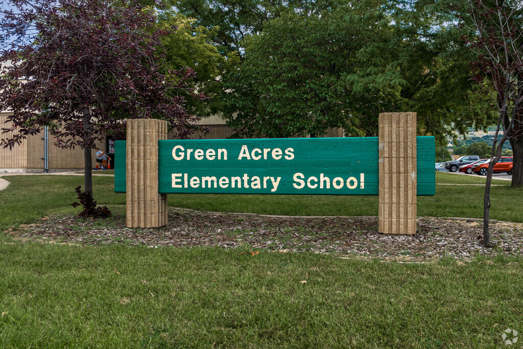 Green Acres Elementary School has a wood sign painted green that is flanked by sturdy brick.