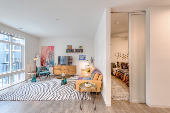 Living area and bedroom with hard surface flooring and sliding barn door