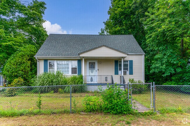 This single-story residence in Hillburn features a glass-paneled front door and a cozy porch with black railings.