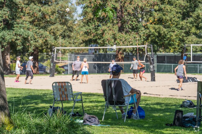 A man enjoys watching sand volleyball from the shade of trees in Buena Vista.