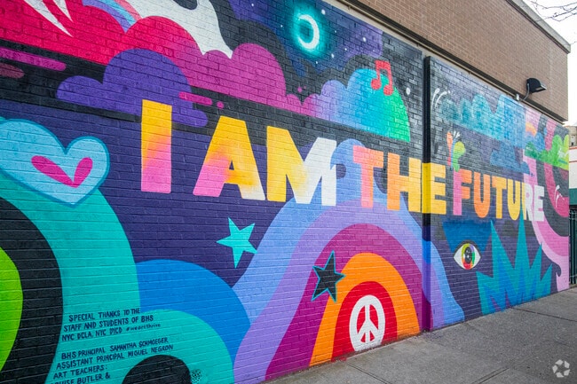 A bright I AM THE FUTURE mural stands outside Boerum Hill School.