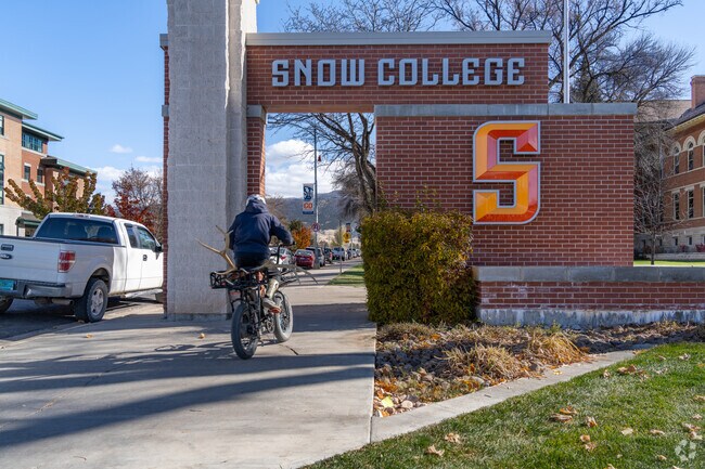 Student rides a bike under the Snow College sign in Ephraim.