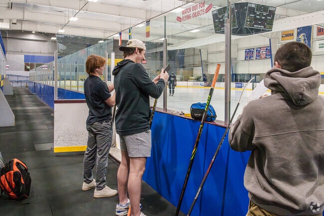 Young hockey players tape up their sticks before practice at IceWorks in Aston Township.