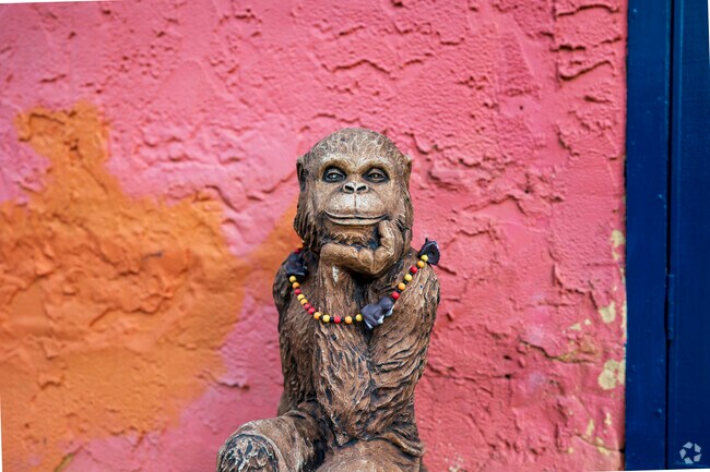 There's a statue of a monkey in a thoughtful pose situated outside the entrance of the 4 Seasons