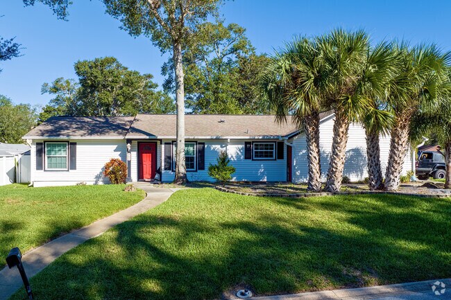 A red front door and large palm trees accent this Northbrook ranch-style home.