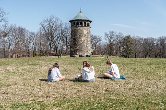 A group of art students sit on the grass to sketch the Rockford Tower just north of Wawaset,