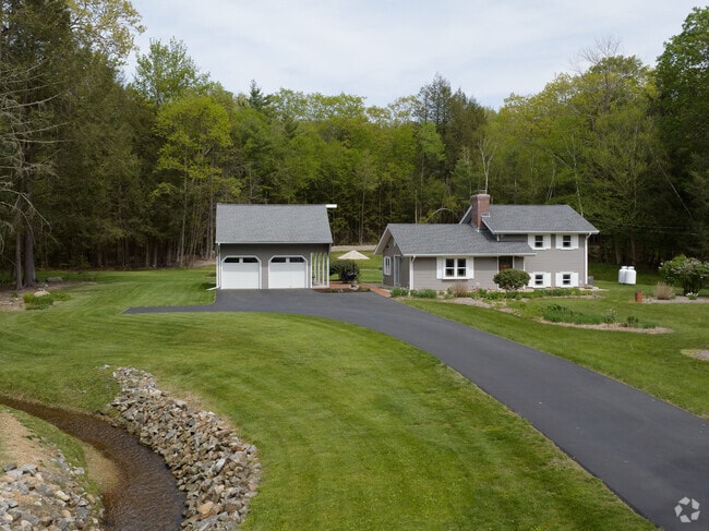 A contemporary-style split ranch with a stream running through the lawn.