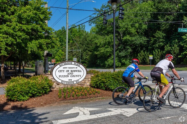 Pair of cyclists leaving the park by the entrance sign.