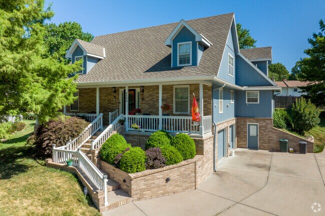 This charming, cottage-inspired home in Sterling, features a wraparound porch, gabled dormers, and a beautifully landscaped entrance that gives it a warm, storybook feel from the street.