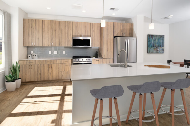 Upgrade Scheme townhome kitchen and dining areas with oak cabinetry, grey tile backsplash, grey quartz countertops, stainless steel appliances, and hard surface flooring