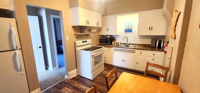 Fully equipped kitchen with oven, microwave, coffee station, and Minnesota-themed art.