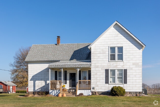 A classic farmhouse with first-floor shutters has a modest front porch in Lenox Township.