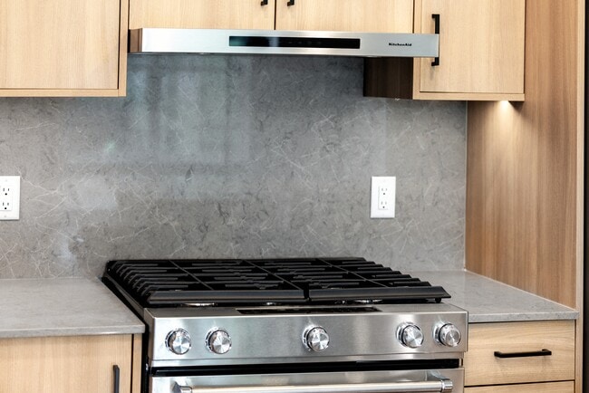 Signature Collection kitchen with stainless steel appliances, quartz countertops, and quartz tile backsplash