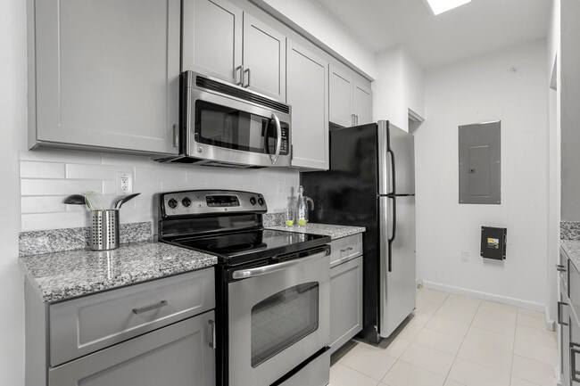 Renovated I Kitchen with grey cabinetry, tile backsplash, tile flooring, and stainless steel appliances