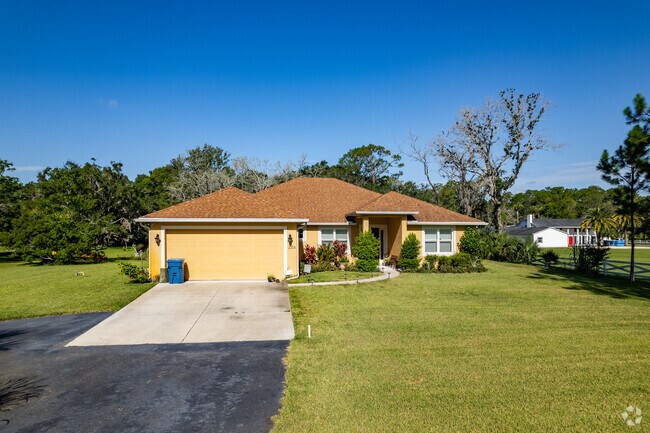A yellow ranch-style home with a driveway in Tomoka Farms.
