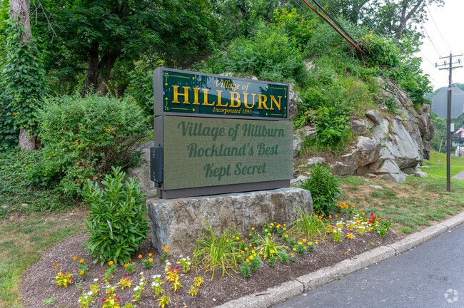 The Village of Hillburn welcome sign, established in 1893, stands on a landscaped stone base near the town entrance.