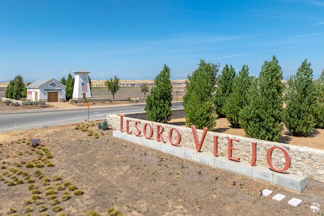 The tree-lined entrance to Tesoro Viejo features a barn.