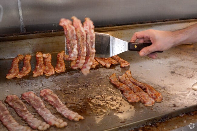 A chef flips sizzling bacon at Tiny's Restaurant in Ayer.