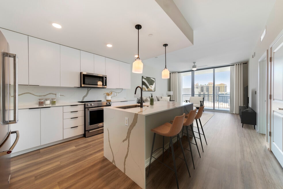 Tower Building - Renovated kitchen with stainless steel appliances, marbled white quartz countertops, light grey cabinetry, and hard surface flooring