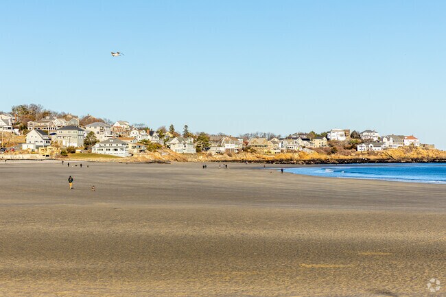 Residents walk along Good Harbor Beach in Gloucester, MA.