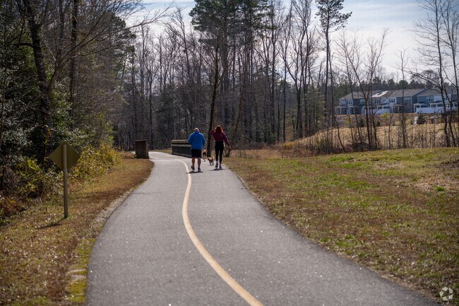 Forestville locals stroll River Bend Park’s riverside greenway shaded by tall trees.