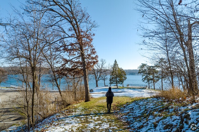 A trail path leading through the woods opening up to the view of the lake.