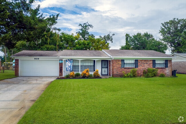 This ranch-style home in neighborhood K features a brick facade and mature trees offering shade.