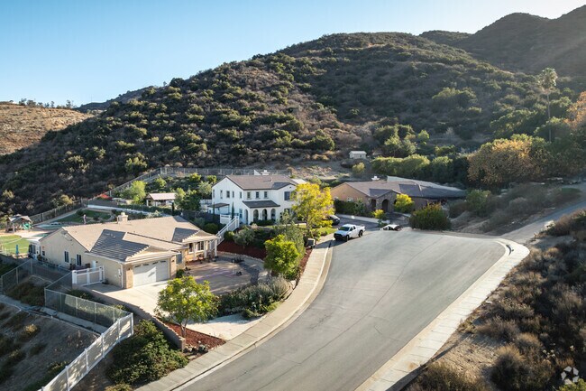 Hillside homes with grassy landscaping are built in Spanish and Craftsman styles.