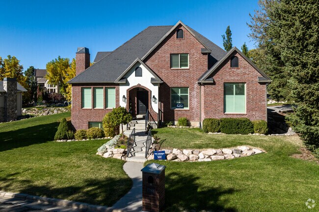 A two-story brick home with a beautifully landscaped front yard.
