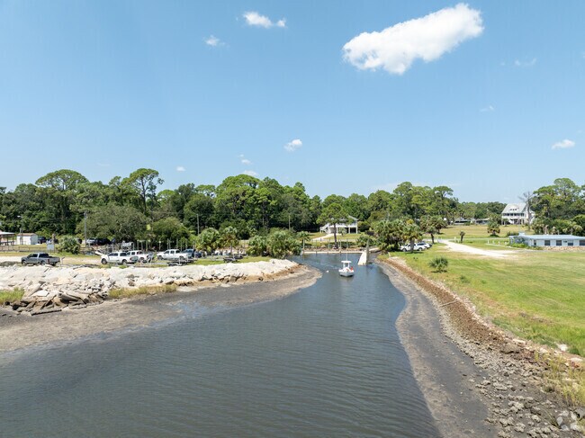 A low‑tide channel and sailboat frame the Lanark Village Boat Club launch.
