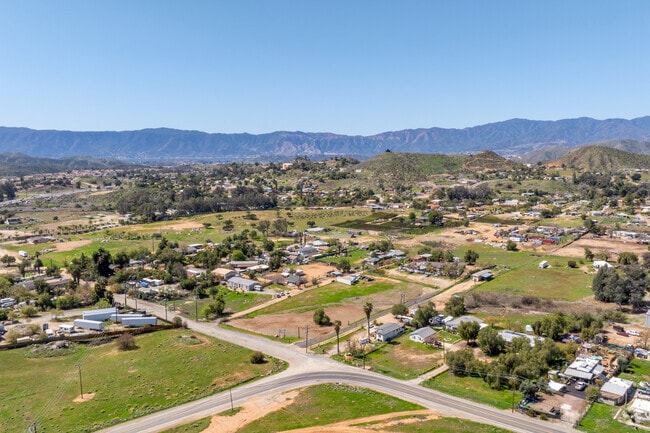 An aerial view of Meadowbrook in Lake Elsinore showcases its peaceful streets, spacious homes, and scenic surroundings, with hills and greenery creating a serene atmosphere.