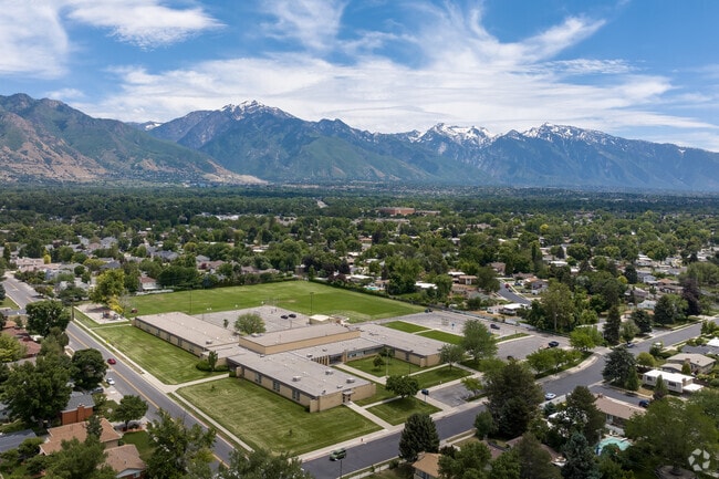 An aerial view of Twin Peaks Elementary School shows snow capped mountains in the background.