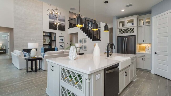 Luxurious kitchen features a sleek white island, sophisticated lighting, and grand staircase at Mostyn Manor Reserve.