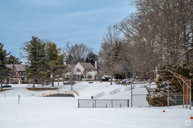 Fox Meadow Park is primarily an open green space with athletic fields and a playground bordered by a wooded area.
