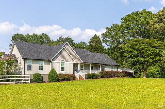A ranch style home sits on a large grassy lot surrounded by trees in the Bolingbroke neighborhood.