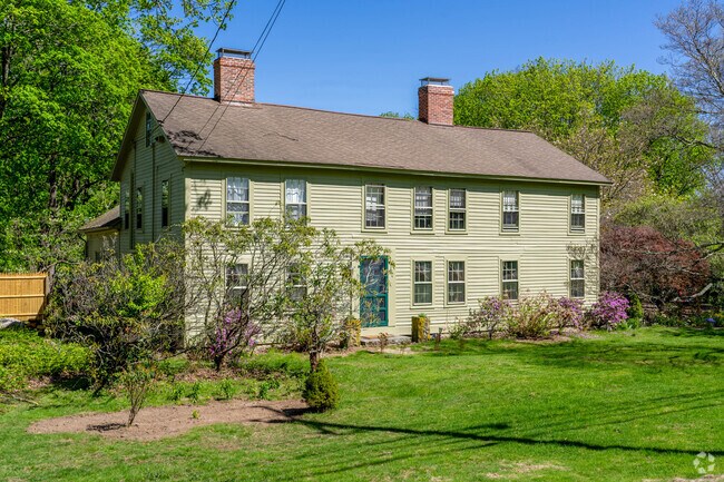A colonial revival style home in Hampton has pale green clapboard siding with two chimneys.