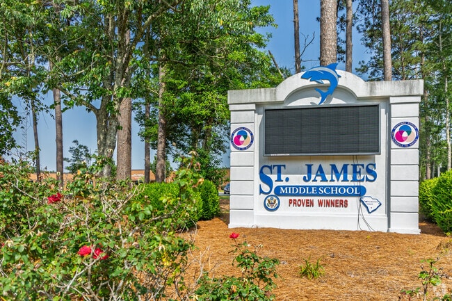 A wide view of St. James Middle School's digital marquee nestled among tall pines.