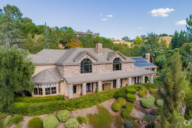 A cobbled mansion is surrounded by green in the Rancho San Miguel
hills.