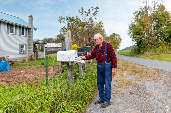 A Gamble resident picks up their mail as their dogs bark playfully in the background.