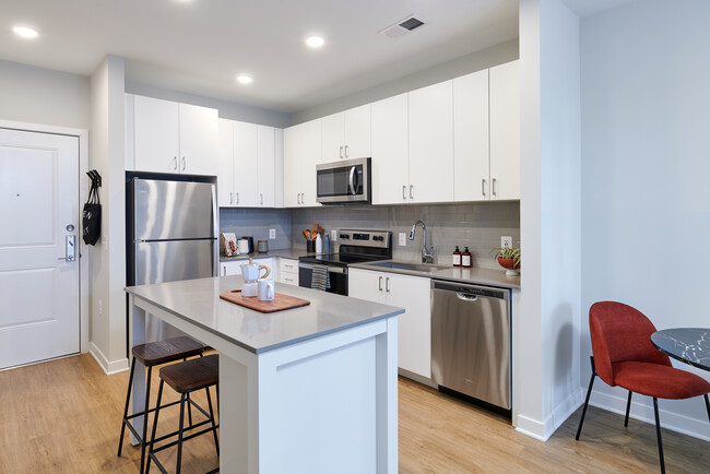 Design Collection II kitchen with white cabinetry, grey tile backsplash, grey quartz countertops, and stainless steel appliances