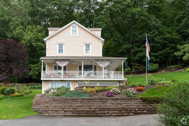 This is a farmhouse perched on a hill with wrap-around porch and a bay window in Trucksville.