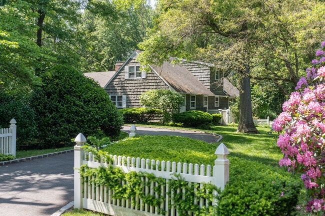 This historic Old Brookville home features wood shingles and a classic cross-gabled roof.