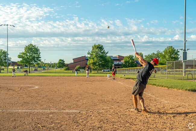 A little league baseball coach hits a ball towards his outfield.