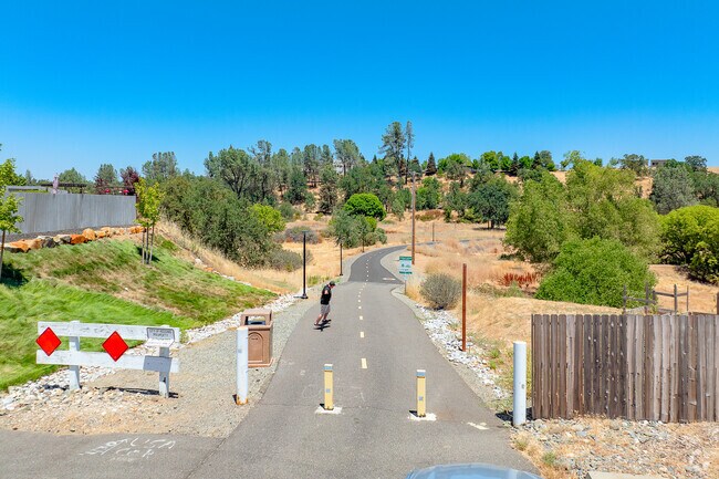 Man rides skateboard down paved trails near Boulder Creek.