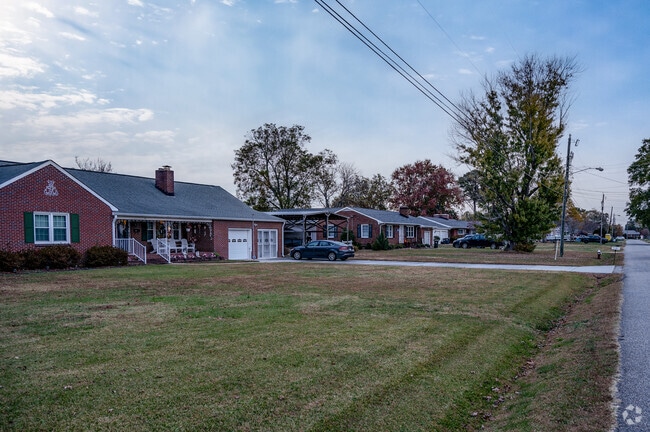 A row of brick ranches in Poquoson West at twilight.