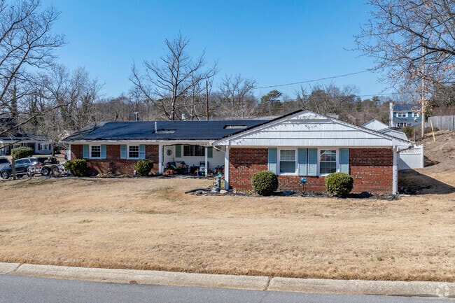 A brick ranch home with solar panels on the roof and a spacious yard in Overbrook.